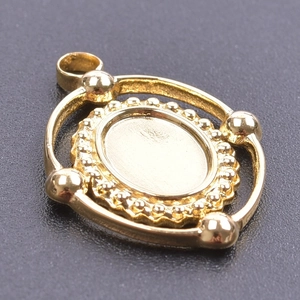 Detailed close-up of golden oval pendant base with beaded edges and four spherical accents