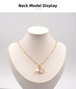 Detail of gold chain necklace featuring a white pearl and shell pendant on a neck model