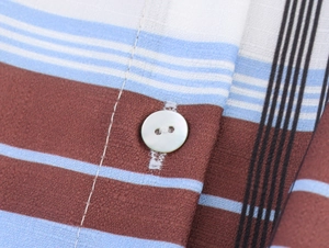 Close-up of brown and blue striped fabric texture with a white button on a shirt dress