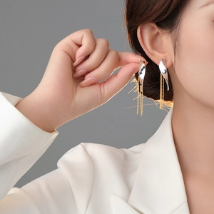 Detail shot of bicolor gold and silver leaf tassel earrings worn by a model