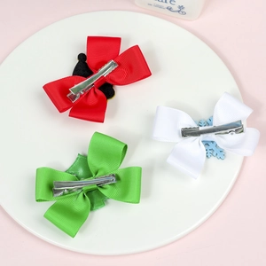 Detail of red white and green festive ribbon bow hair clips on a white ceramic plate