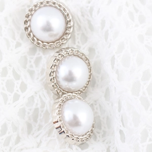 Elegant white pearl buttons with silver chain borders on delicate lace background