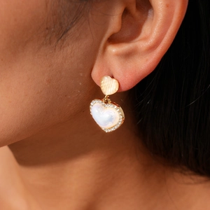 Detail of heart-shaped gold drop earrings with pearl luster and sparkling crystals