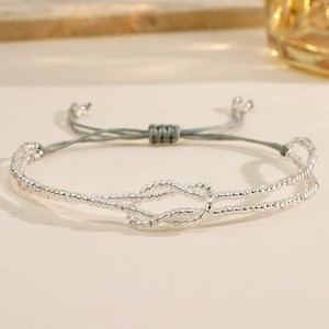 Close-up of bohemian silver bead bracelet with hand-woven adjustable grey cord