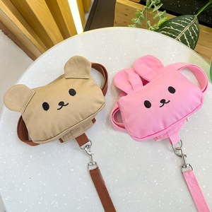 Detalle de mochilas para mascotas de oso y conejo con ganchos de metal sobre mármol