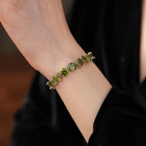 Detail of silver tennis bracelet with olive green round zircon stones on black velvet