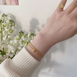 Close-up of gold double-layer chain bracelet and letter I engraved ring on model