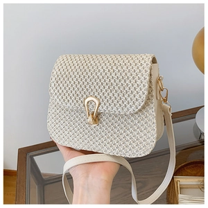 Detail of woven crossbody bag with gold horseshoe clasp and fine cream texture