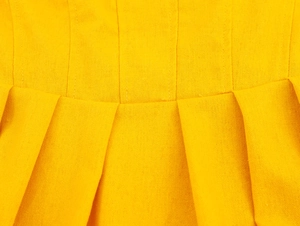 Detailed macro view of yellow pleated fabric texture and vertical stitching craftsmanship