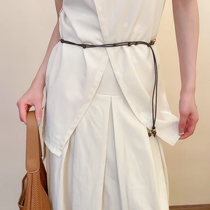 Detailed view of dark brown pearl beaded waist belt styled on an elegant off-white suit