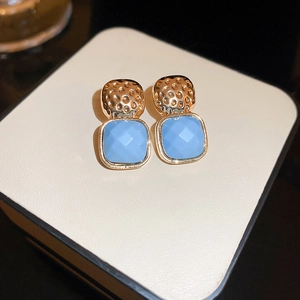 Detailed macro view of vintage golden hammered earrings with blue faceted square gems