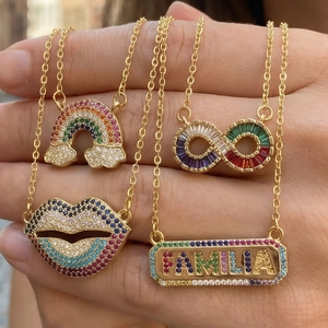Detail of four gold necklaces with rainbow, infinity, red lips and FAMILIA pendants