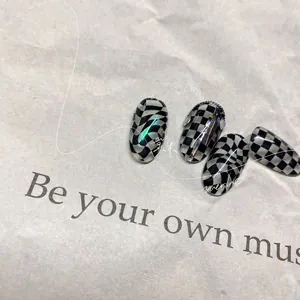 Dettaglio di adesivi per unghie a scacchi bianchi e neri con laser verde e decoro a catena