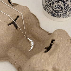 Detailed close-up of a crescent croissant pendant necklace in polished silver finish