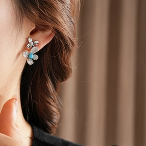 Macro shot of silver flower earrings with zircon pavé and turquoise center on model