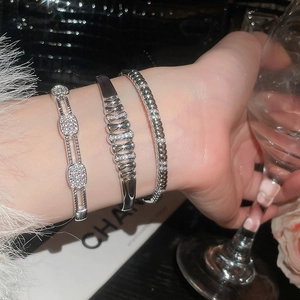 Macro view of three luxury silver bangles with pavé zircons and hollow woven patterns