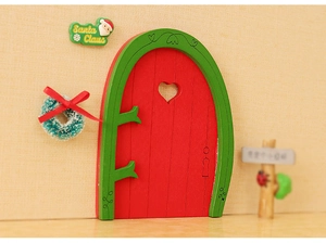 Close-up of a miniature red Christmas dollhouse door with a green wreath and Santa decor