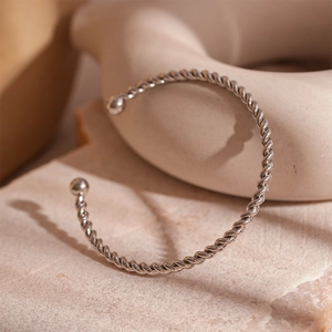 Detail of silver twisted metal cuff bracelet with spherical ends on a stone base
