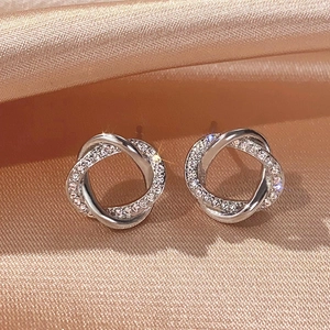 Close-up of silver intertwined hoop earrings with sparkling cubic zirconia on silk