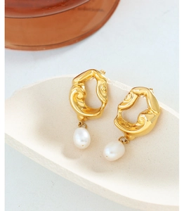 Macro detail of 18K gold-plated lava earrings with elegant white freshwater pearl pendants