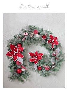 Close-up of artificial cedar wreath with pine cones and red poinsettia on white fabric
