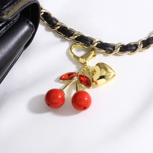 Bijou de sac cerise tendance avec perles rouges et cœur doré sur une chaîne noire