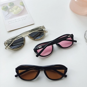 Flat lay of vintage oversized sunglasses in black, tea, and transparent frames on a white desk