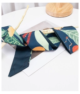 Detail of silk hair scarf with orange fruit print wrapped on branch, navy blue satin