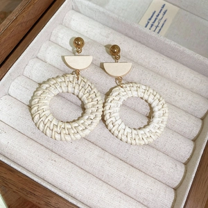 Detailed texture of bohemian straw woven round drop earrings in a wooden jewelry box