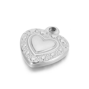 Macro shot of silver heart pendant with embossed dot pattern on a clean white background