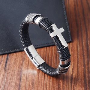 Bracelet tressé en cuir noir pour homme avec croix en métal sur une table en bois
