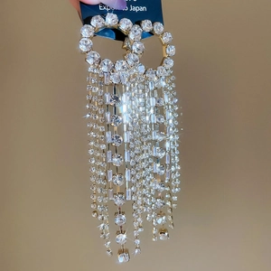 Detail of luxury long tassel earrings with sparkling rhinestones and golden finish
