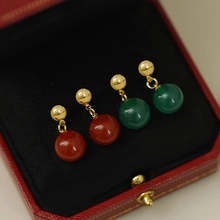 Detailed close-up of red and green zircon earrings displayed in a luxury jewelry box