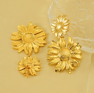 Close-up of gold sunflower drop earrings with hammered metal texture on silk background
