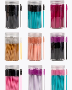 Detailed macro view of multi-color disposable eyelash brushes in transparent tube storage