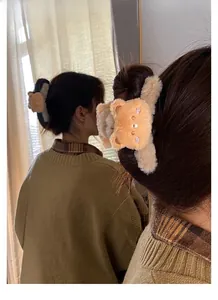 Detail of plush brown bear hair claw clip with pink embroidery shown on model