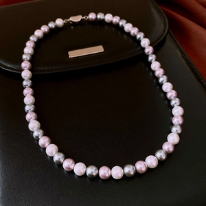 Detailed close-up of multi-color pearls with a heart-shaped silver metal clasp detail