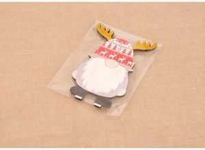 Flat wooden Christmas gnome ornament with reindeer antlers in clear plastic packaging