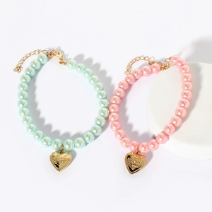Detail of dog collars featuring colorful pearls and engraved gold heart pendants