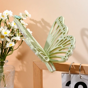 Detailaufnahme einer mattgrünen Schmetterlings-Haarklammer mit filigranen Aussparungen