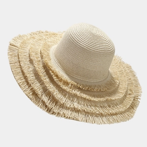 Close-up of beige wide-brim straw hat featuring tiered fringed edges and woven texture