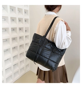 Close-up of a black quilted down tote bag with glossy finish on a stylish model