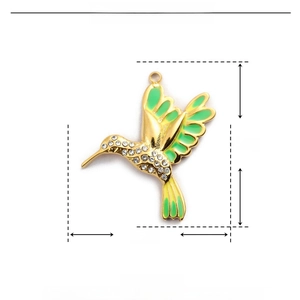 Dettaglio macro del ciondolo a colibrì con smalto verde, strass e misura di 28 mm