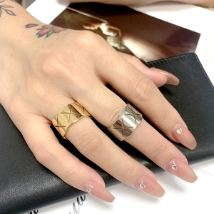 Detailed view of wide gold and silver titanium steel rings with cross-rhombus patterns