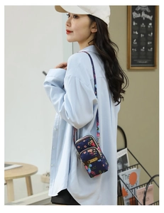 Detailed view of mini floral nylon crossbody bag with zipper compartments worn by a model