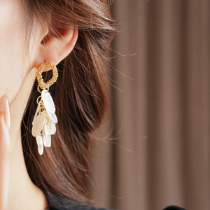 Detail shot of long tassel earrings with golden rings and layered white shell disks