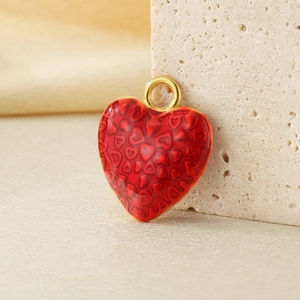 Detailed view of a red enamel heart pendant with embossed patterns and a gold loop clasp