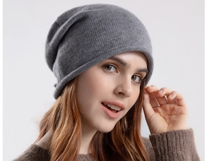 Detail of grey knitted slouchy beanie showing soft wool texture and rolled edge on female model