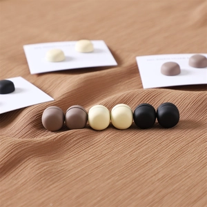 Matte finish magnetic scarf buckles in brown, cream and black on textured fabric