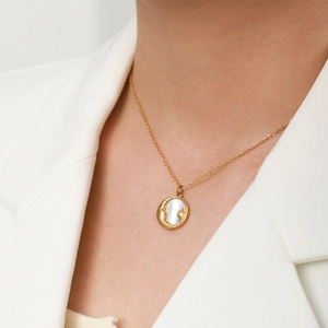 Close-up of mother-of-pearl sun and moon pendant necklace on a gold chain
